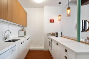 una cocina con armarios blancos y fregadero en Parisian Apartment With Terrace in Saint Michel-Notre Dame en París