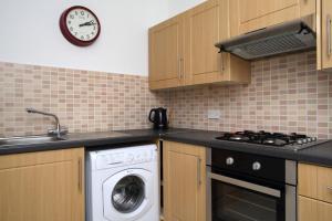 a kitchen with a washing machine and a clock on the wall at Stylish 2 Bedroom Bruntsfield Apartment in Edinburgh in Edinburgh