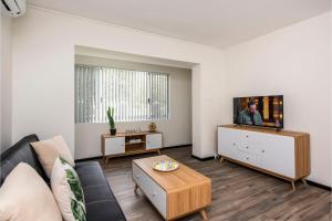 a living room with a couch and a tv at Stylish Apartment in Leafy South Perth in Perth