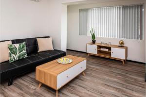 a living room with a black couch and a coffee table at Stylish Apartment in Leafy South Perth in Perth