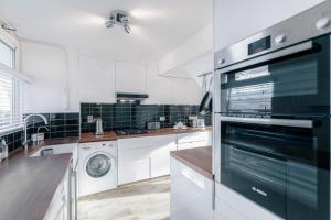 ロンドンにあるModern 3 Bedroom Apartment in Brixtonのキッチン(白いキャビネット、洗濯機、乾燥機付)