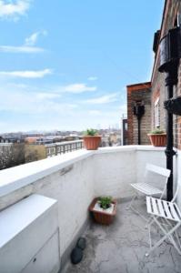 a balcony with a bench and chairs on a building at Stylish 2 Bedroom Apartment Between Camden Town Primrose Hill in London