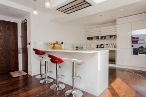 ロンドンにあるBeautiful Newly Renovated 2 Bed Apartment in Bankのキッチン(白いカウンター、赤いスツール付)