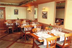 a restaurant with wooden tables and chairs and a large mirror at Hôtel de Ville in Gruyères