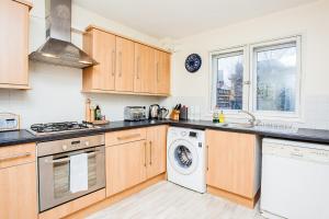 a kitchen with wooden cabinets and a washer and dryer at Modern and Spacious Central 1 Bedroom Apartment with Balcony in London