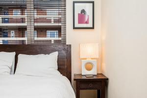 a bedroom with a bed and a table with a lamp at Modern and Spacious Central 1 Bedroom Apartment with Balcony in London