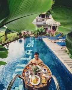 Ein Mann, der an einem Tisch im Pool sitzt. in der Unterkunft Villa Silas in Ubud
