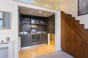 a kitchen with stainless steel appliances and a staircase at Modern 1 bed Flat in Knightsbridge in London