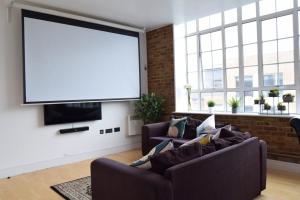 a living room with two couches and a projection screen at Bright Warehouse Conversion in Buzzing Peckham in London