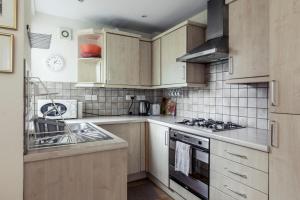 a kitchen with wooden cabinets and a stove top oven at Bright 2 Bedroom Flat in Central London in London