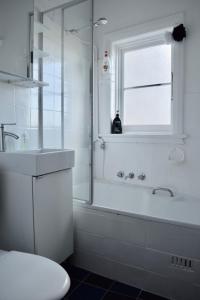 a bathroom with a shower and a tub and a sink at Cosy 3 Bedroom Apartment In Trendy Haberfield in Sydney