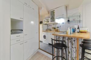 パリにあるCharming 2 Bedroom Apartment in the Heart of Parisの白いキャビネット、テーブルと椅子付きのキッチンが備わります。
