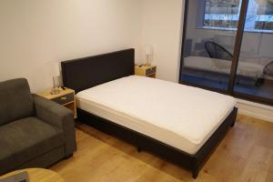 a bedroom with a bed and a couch and a window at Modern Cosy Studio Apartment Auckland Central in Auckland