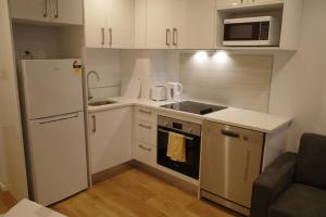 a small kitchen with a refrigerator and a microwave at Modern Cosy Studio Apartment Auckland Central in Auckland