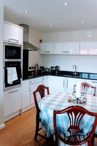 エディンバラにあるModern Apartment in Edinburghのキッチン(テーブル、椅子付)、キッチン(白いキャビネット付)