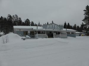 un estacionamiento cubierto de nieve con un edificio de mujeres en Motel Willis West, en Ruka