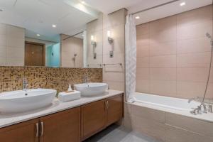 a bathroom with two sinks and a tub and a shower at Luxury Apartment on The palm Close to Nakheel Mall in Dubai
