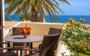 una mesa y sillas en un patio con vistas al océano en Algar Seco Parque, en Carvoeiro