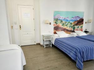 a bedroom with two beds and a painting on the wall at Ronda Hotel Polo in Ronda
