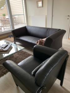 a black leather couch in a living room at ORCHIS Duplex in Knokke-Heist