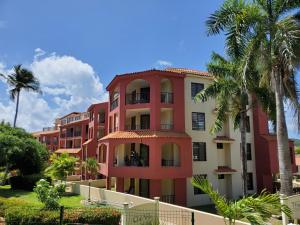 a red building with palm trees in front of it at The Village at Palmas del Mar in Humacao