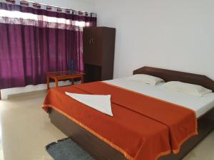 - une chambre dotée d'un lit avec une couverture rouge et orange dans l'établissement Blue Lagoon Resort, Neil Island, à Neil Island