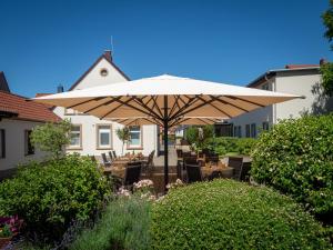 un grande ombrellone in un giardino con tavoli e sedie di Hotel Schaper a Celle
