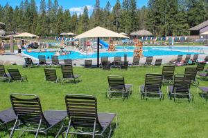 um grupo de cadeiras e guarda-sóis na relva perto de uma piscina em Meadow House 30 | Discover Sunriver em Sunriver