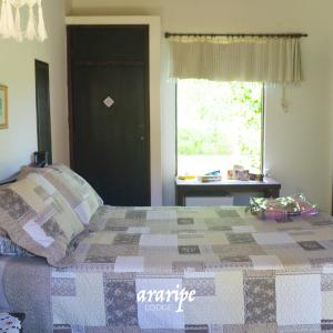 Araripe Lodge في Saubara: غرفة نوم عليها سرير ولحاف