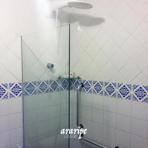 y baño con ducha y azulejos azules y blancos. en Araripe Lodge, en Saubara