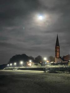 budynek z wieżą zegarową w nocy z księżycem w obiekcie kormoran-sarbinowo w Sarbinowie