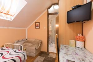 a room with a crib and a tv on the wall at Guest House Bagi in Požega