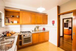 a kitchen with wooden cabinets and a sink at Casa da Torre com garagem gratuito in Aveiro