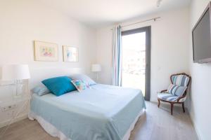 Un dormitorio blanco con una cama y una silla. en Apartamento en Port Marina Palamos, en Palamós
