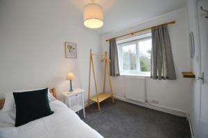 a bedroom with a white bed and a window at Orchard Cottage in Cornhill-on-tweed