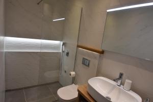 Un baño con lavabo, inodoro y espejo. en Villa NEDE, en Podgora 31 fotos más