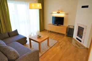 a living room with a couch and a tv at Smėlio Vila Apartments in Palanga