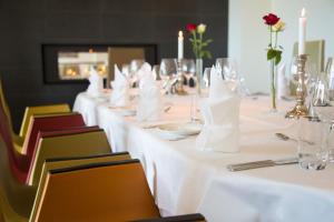a long table with white tables and chairs with candles at Havila Hotel Ivar Aasen in &Oslash;rsta