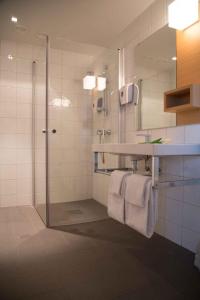 ein Bad mit einer Dusche, einem Waschbecken und einem Spiegel in der Unterkunft Havila Hotel Ivar Aasen in Ørsta