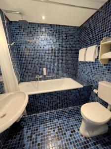 a blue tiled bathroom with a tub and a toilet at Hotel restaurant Stad Munster in Winterswijk