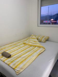ein Bett mit gestreifter Decke mit Fenster in der Unterkunft Apartman Glišić 2 in Bajina Bašta