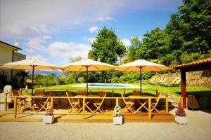 un patio con mesas, sombrillas y una piscina en Quinta do Bento, en Vieira do Minho