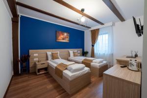a bedroom with two beds and a blue wall at Escala Rooms in Ghimbav