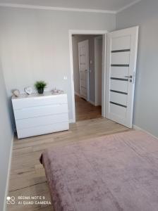 a white room with a bed and a dresser at Apartament Mazury Węgorzewo in Węgorzewo