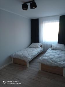 a bedroom with two beds and a window at Apartament Mazury Węgorzewo in Węgorzewo