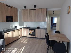 a kitchen with wooden cabinets and a table and a dining room at Apartament Mazury Węgorzewo in Węgorzewo