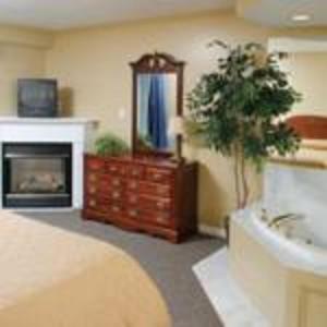 a bedroom with a bed and a fireplace and a mirror at InnSeason Resorts Captain's Quarters in Falmouth