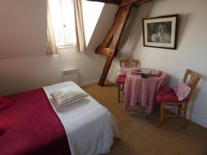 a bedroom with a bed and a table and chairs at Les Petits Matins Bleus - Chambres d'hôtes "Les Pommiers" in Sainte-Marguerite-de-Viette