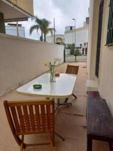a white table with chairs and a vase of flowers on it at baia verde appartamento 150 m dal mare in Gallipoli +7 photos
