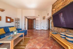 Una sala de estar con un sofá azul y un televisor. en CASA CON VISTA MARE, en Cala Gonone